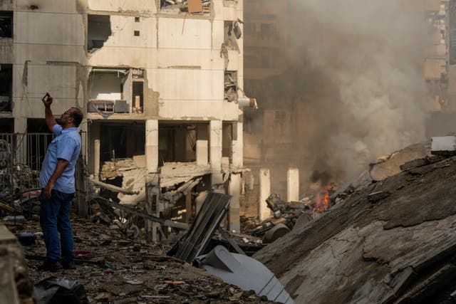 A man documents the damaged buildings at the site of an Israeli airstrike in Beirut’s southern suburb