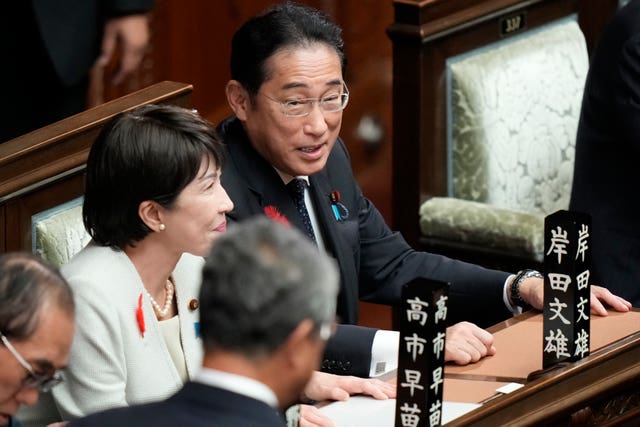 Outgoing prime minister Fumio Kishida, right, sits in the parliament’s lower house