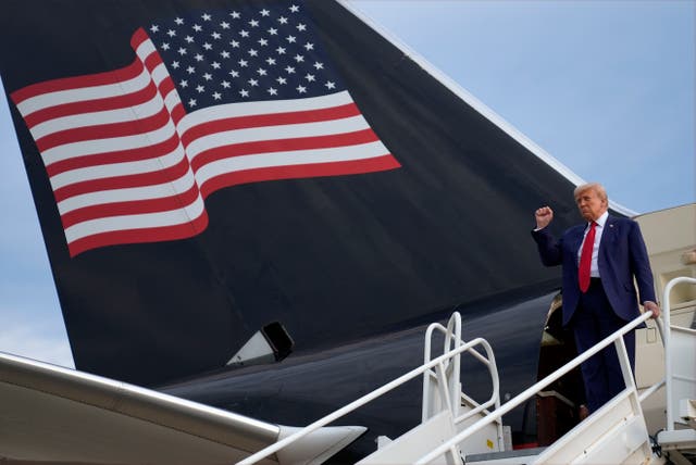 Donald Trump holds a fist in the air as he embarks from a plane