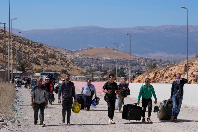 People carrying luggage on an empty road