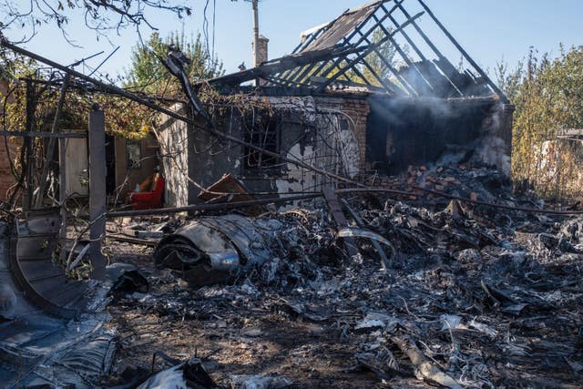 A damaged private house in the background of fragments of a shot down Russian military plane