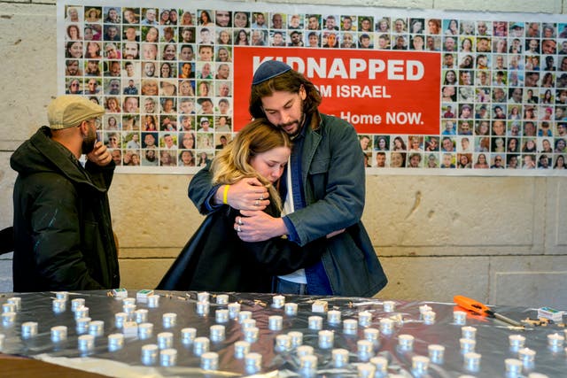 People embrace after lightning candles at a ceremony marking the first anniversary of the Hamas spearheaded attacks on Israel, at the synagogue of the Chabad community in Berlin, 