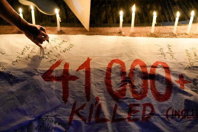 Activists light candles and write the names of Palestinian casualties on a banner as they hold a pro-Palestinian rally to mark the one-year anniversary of the Israel Hamas war 