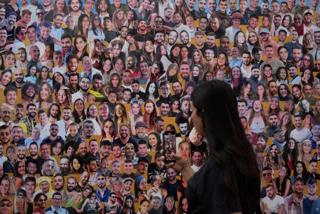 An attendant walks through a mural with portraits of the victims at the site of the Nova music festival,