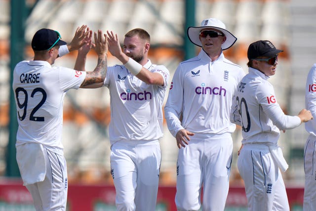 Gus Atkinson high fives a teammate after taking a wicket