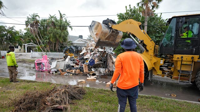 Crews using a yellow digger working to remove the debris from a road