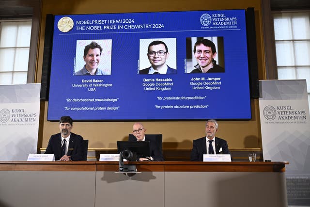 The Nobel Committee for Chemistry sitting beneath pictures of the winners