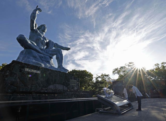 A visitor prays in front of the Peace Statue at the Peace Park in Nagasaki