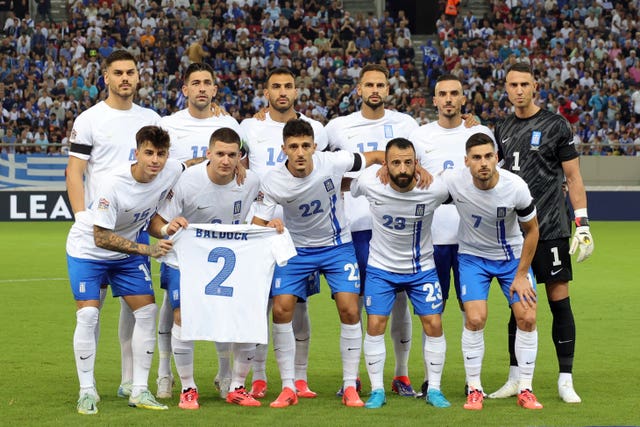 Greece players pose with a shirt of team-mate George Baldock