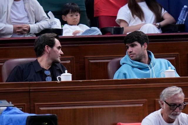 Roger Federer, left talks to Carlos Alcaraz in the stands