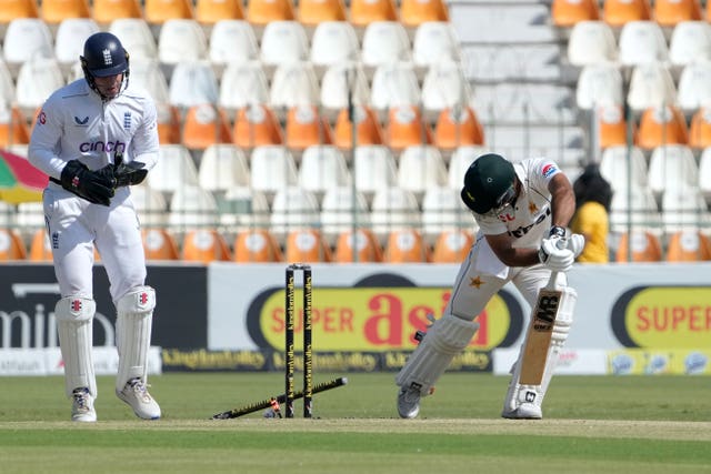 Abdullah Shafique watches behind him as the ball from Jack Leach removes his stump from the ground