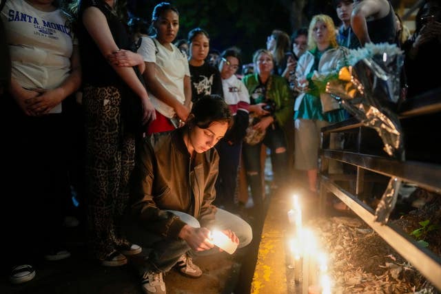 A person lights a candle in tribute