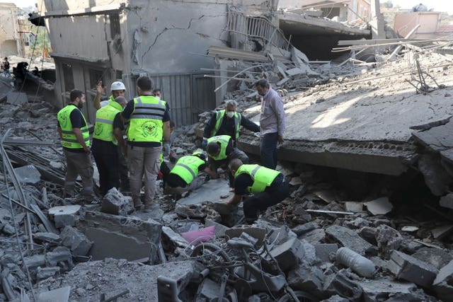 Rescue workers remove rubble, as they search for victims at the site that was hit by Israeli air strikes in Qana, south Lebanon