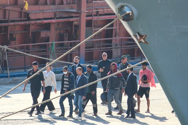 Migrantw and security officials walk at the port of Shengjin, northwestern Albania