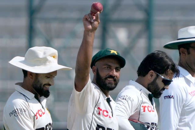 Sajid Khan, wearing a cap, holds up the ball after taking seven wickets for Pakistan against England