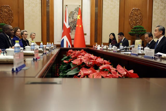 David Lammy, left, sits with a British delegation across the table from Chinese foreign minister Wang Yi and other officials during a meeting in Beijing. The British and Chinese flags hang in the background.