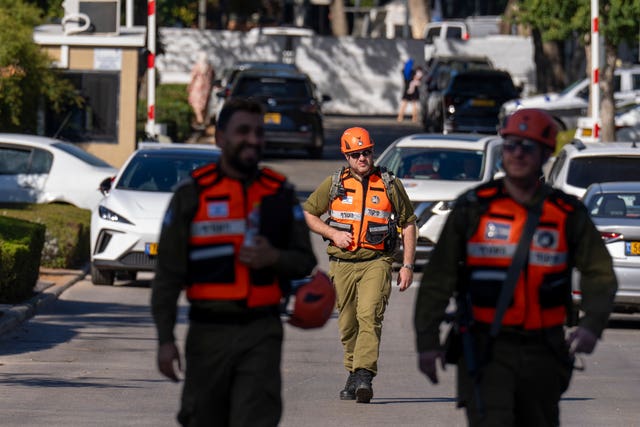 Officers from the Israeli Home Front Command military unit walk on a road near where Israel’s government says a drone launched toward Israeli Prime Minister Benjamin Netanyahu’s house in Caesarea, Israel, Saturday, Oct. 19, 2024