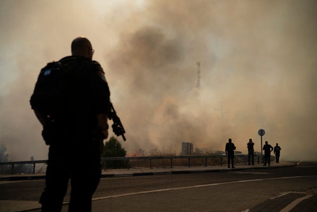 Smoke rises as a police officer watches