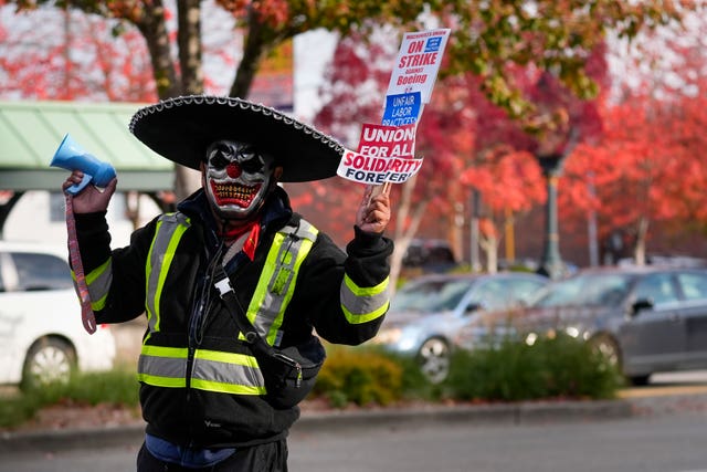 Boeing mechanic Eugenio, who preferred not to give a last name, sounds a bullhorn while holding a sign