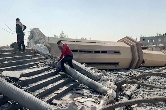 People observe a mosque destroyed by Israeli air strikes in the city of Khan Younis,