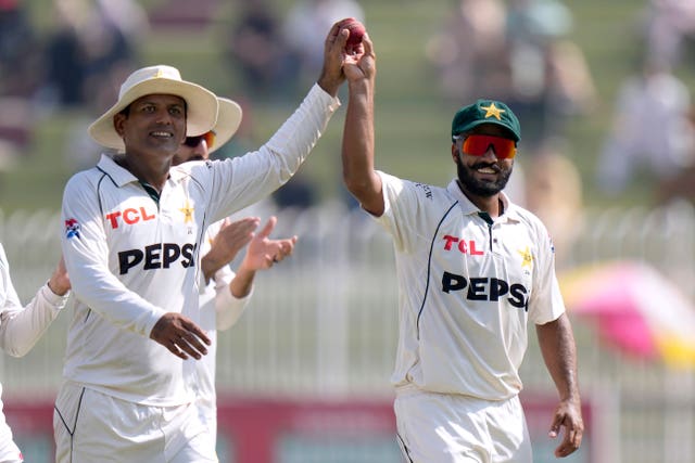 Noman Ali, left, and Sajid Khan both raise the match ball as they walk off the pitch