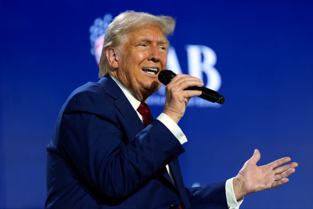 Donald Trump speaking into a microphone while sitting on stage