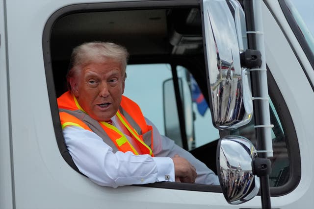 Donald Trump talks to reporters as he sits in a garbage truck