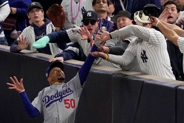 Fans interfere with a foul ball caught by Los Angeles Dodgers right fielder Mookie Betts