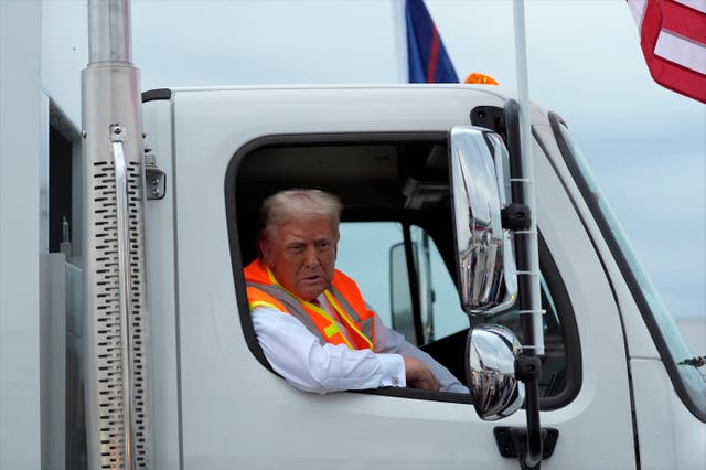 Donald Trump talks to reporters as he sits in a garbage truck