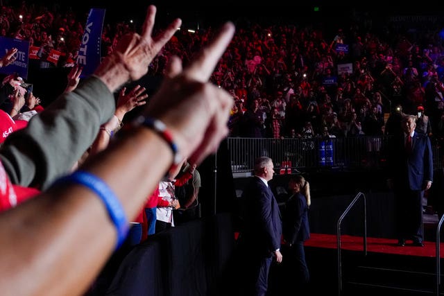 Hands raise in salute above Donald Trump 