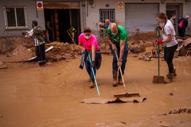 People clean the street of mud in an area affected by floods in Valencia, Spain, Saturday, Nov. 2, 2024.