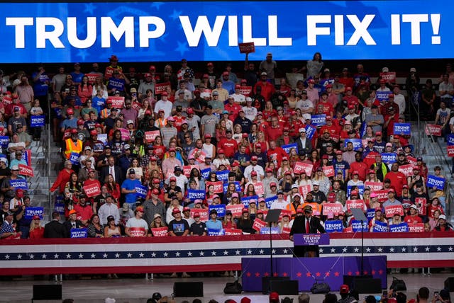 Donald Trump speaks before a 'Trump Will Fix It' banner