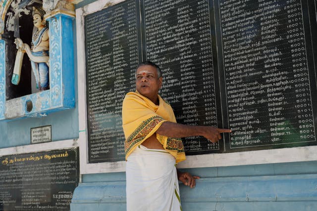 A priest points out Kamala Harris's name on a plaque