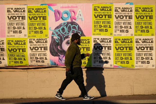 A man walks past a wall covered with voting flyers