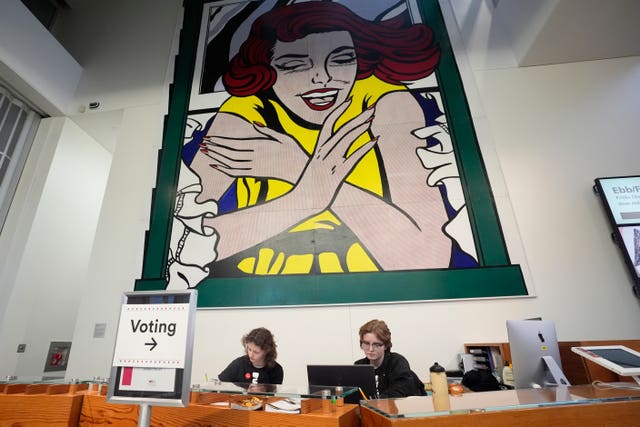 Event assistants Katie Papador, left, and Maddy Wittmers-Grave sit at the entrance of a polling location at the Weisman Art Museum in Minneapolis