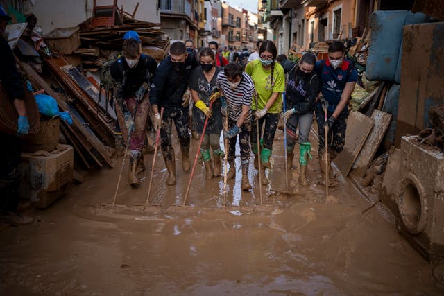 Volunteers and residents clean the mud from the streets in an area affected by floods in Paiporta, Valencia, Spain