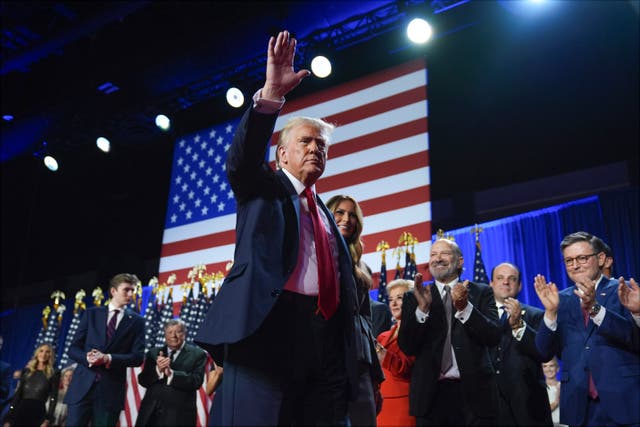 Donald Trump waves as he walks with wife Melania at his election night party at the Palm Beach Convention Centre