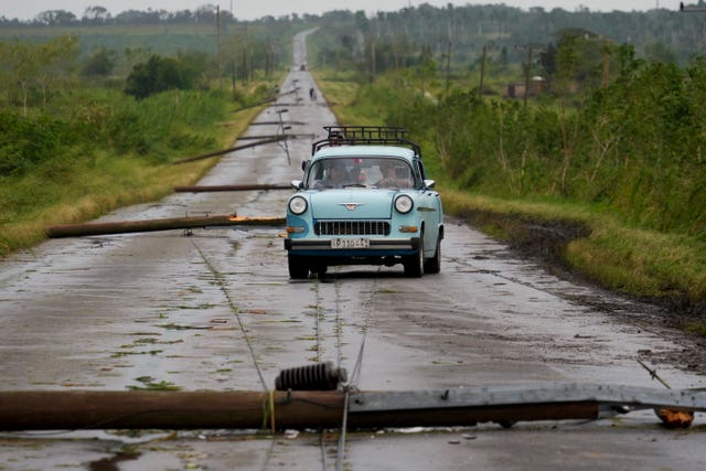 A car on a road littered with fallen power lines