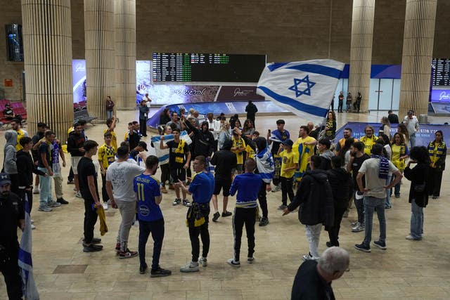 People welcome Maccabi Tel Aviv soccer fans as they arrive at Israel’s Ben-Gurion International Airport