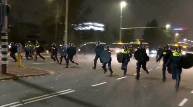 Police in riot gear run towards protesters, after pro-Palestinian supporters marched near the football stadium, in Amsterdam, Netherlands