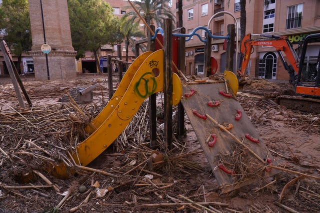 A children’s slide in a playground is covered with debris 