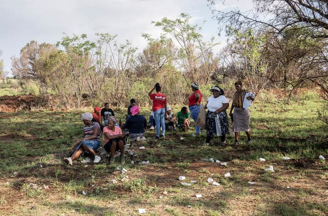 Relatives of miners and community members wait at a mine shaft