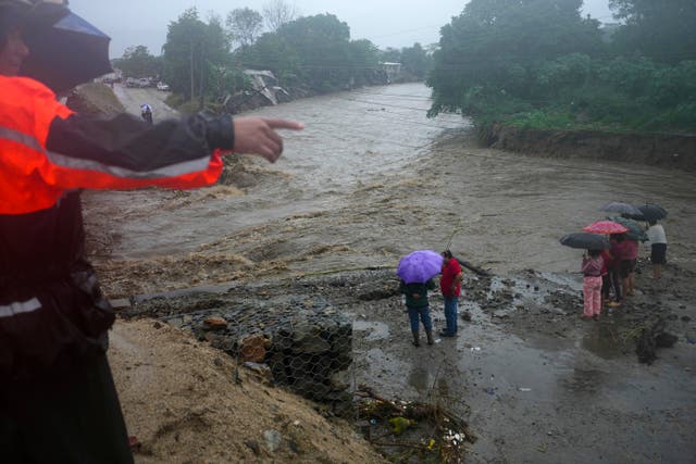 Residents stand alongside the banks of a river on the outskirts of San Pedro Sula, Honduras