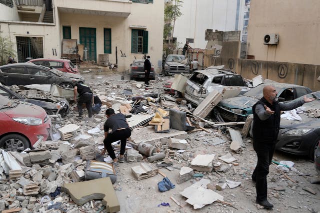 People search through the rubble of a destroyed building at the site of an Israeli air strike in central Beirut