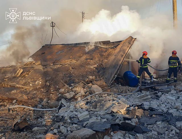 Emergency services personnel work to extinguish a fire following a Russian rocket attack in Lviv, Ukraine 