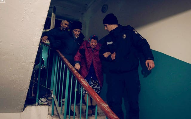 A police officer evacuates an elderly resident following a Russian rocket attack that hit a multi-storey apartment building in Sumy, Ukraine 