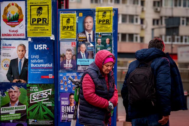 People walk past panels displaying electoral posters ahead of the presidential elections in Bucharest, Romania 