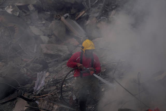 Firefighter uses water hose amid rubble