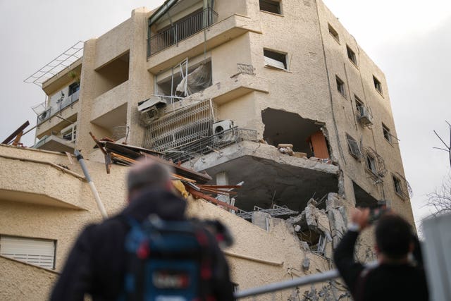 Journalists take pictures of a building hit direct by a rocket fired from Lebanon in Haifa, Israel