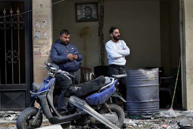 Lebanese men stand outside their damaged shop,